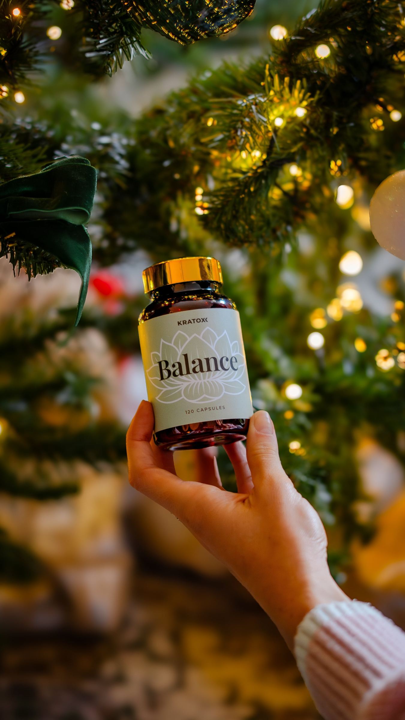 Hand holding Balance beside a Christmas tree