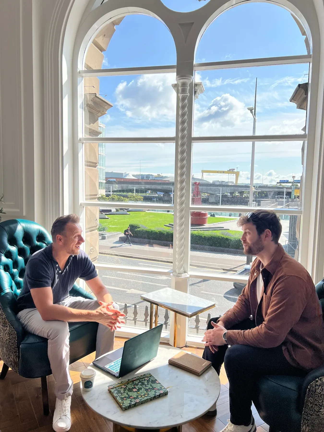 Two people talking beside a large sunlit window