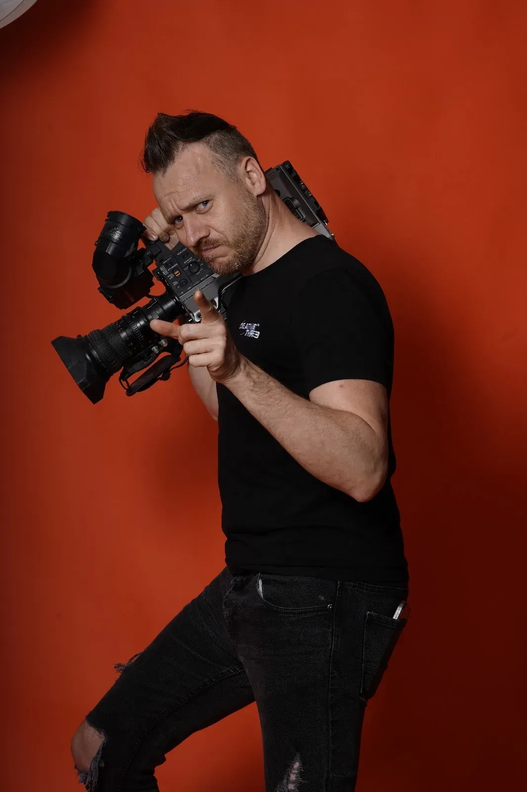 Photographer holding a camera against an orange background