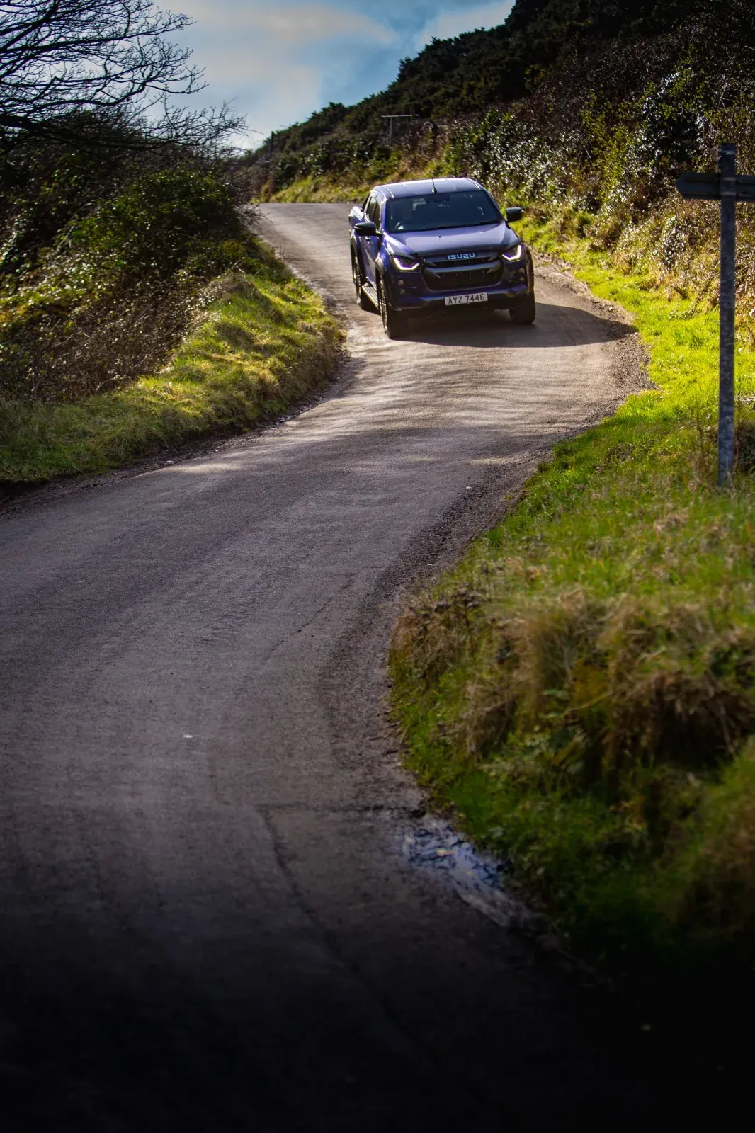 Blue pickup driving along a narrow country road
