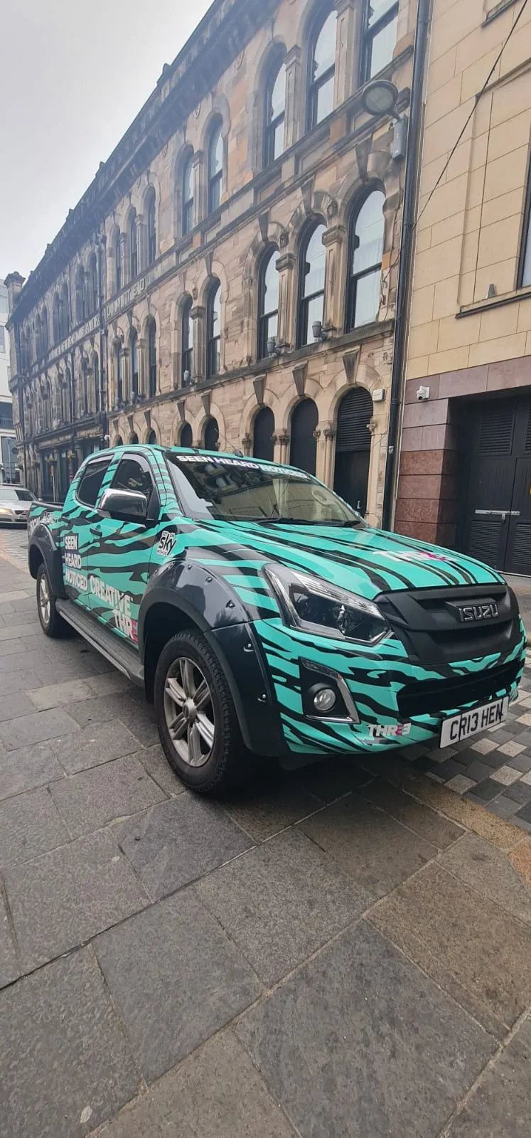 Green patterned pickup on a city street